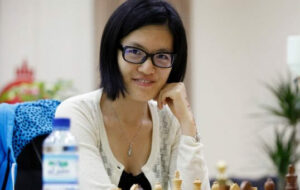 Schach-Weltmeisterin Hou Yifan am Schachbrett mit Blick in die Kamera.